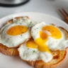 Two perfectly cooked over easy eggs on toast with crispy edges and runny yolks, garnished with black pepper and fresh herbs for a delicious breakfast