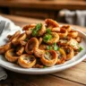 Close-up of sautéed Lion's Mane mushrooms on a white plate, garnished with fresh parsley, served on a wooden table in a cozy home kitchen setting