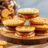 Close-up of Rolo-Ritz Sandwiches with melted caramel and chocolate filling between crispy Ritz crackers, garnished with sea salt, on a wooden board