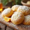 Traditional Italian Ricciarelli honey cookies dusted with powdered sugar, served on a rustic wooden table with a jar of golden honey, almond slices, and fresh orange slices