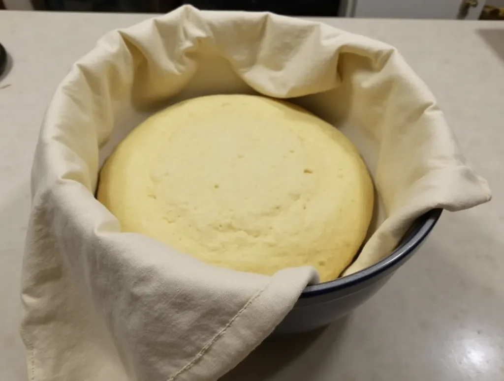 Dough for Swiss Gipfeli resting under a cloth on the counter