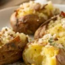 Crispy Caesar Smashed Potatoes served in a plain white plate with golden edges, drizzled with Caesar dressing, and topped with fresh parsley.