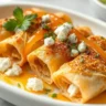 A close-up shot of crispy phyllo rolls filled with feta cheese and topped with hot honey drizzle, served in a white dish with natural, soft daylight.