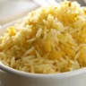 A close-up of Golden Butter Rice served in a white ceramic dish with soft, diffused natural lighting