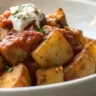 Close-up of Easy Patatas Bravas served on a white plate with a rich, crispy texture and a tangy Bravas sauce