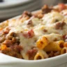 Classic Midwestern Johnny Marzetti Pasta Bake served in a white ceramic dish with soft, natural lighting highlighting its rich textures