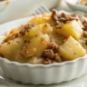 Close-up shot of Hungarian Potato Casserole in a white ceramic dish with natural lighting