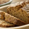 Close-up of freshly baked Irish Brown Bread in a cream-colored dish with a golden-brown crust and soft crumb, naturally lit