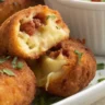 Chorizo, Cheese, and Potato Croquettes served with avocado aioli in a white dish, featuring a crispy golden crust and gooey cheese filling.