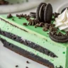 Close-up of a creamy green velvet Oreo cheesecake slice with crunchy Oreo crust on a white plate