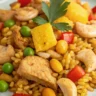 Close-up of pineapple chicken fried rice with chicken, vegetables, and pineapple chunks served on a white plate
