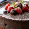 Flourless Chocolate Cake slice on white plate with powdered sugar and berries