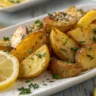 Crispy Greek Lemon Potatoes served on a white plate with lemon wedges and parsley garnish