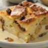 Best Ever Bread Pudding with golden crust and vanilla sauce served on a white plate