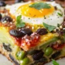 Close-up of freshly baked Black Bean Egg Bake with cheese, black beans, and peppers on a white plate