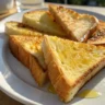 Crispy golden fried bread slices served on a white plate in natural light.
