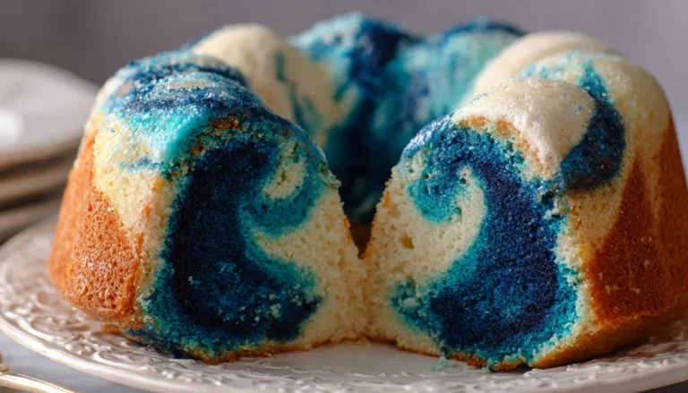Blue velvet swirl pound cake sliced on white cake stand showing marbled blue and vanilla interior