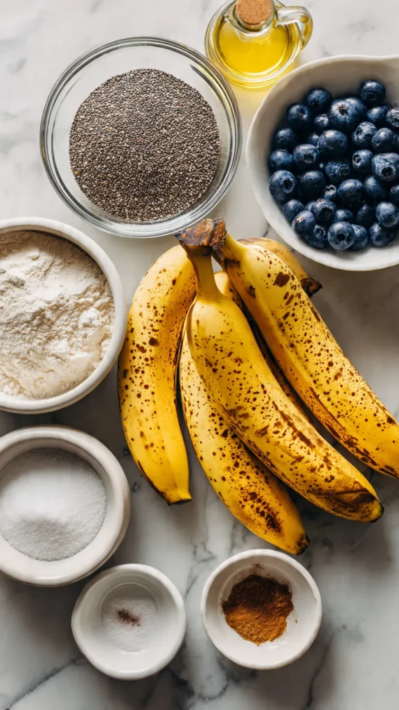 All the ingredients needed to make vegan gluten-free banana bread with buckwheat flour, chia seeds as egg replacement, and fresh blueberries