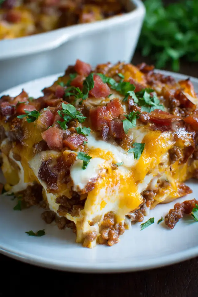 Meat lovers pizza casserole with melted cheese, pepperoni, and bacon in a white baking dish on wooden table