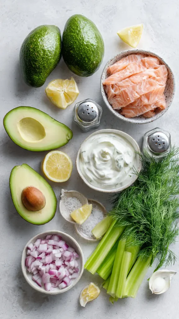 Ingredients for salmon-stuffed avocado laid out including canned salmon, avocados, Greek yogurt, and fresh herbs