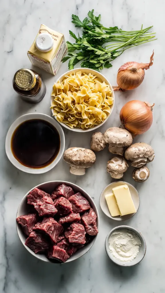 Overhead view of ingredients for crockpot beef and noodles including beef chunks, egg noodles, vegetables, and seasonings on marble counter
