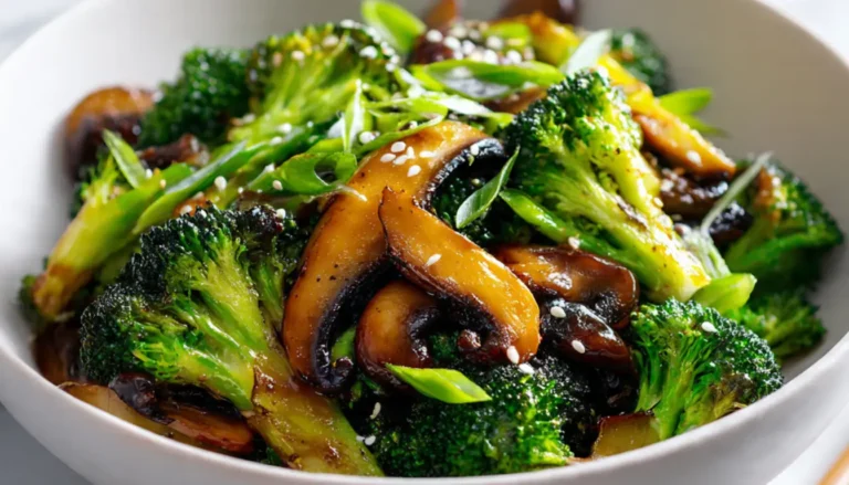 Vibrant broccoli and mushroom stir fry in white bowl with sesame seeds and green onions garnish