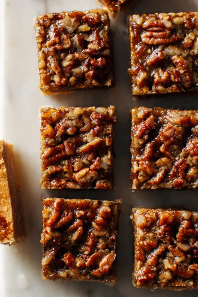 Lazy girl pecan pie bars cut into squares on a marble board showing golden caramel filling and shortbread crust