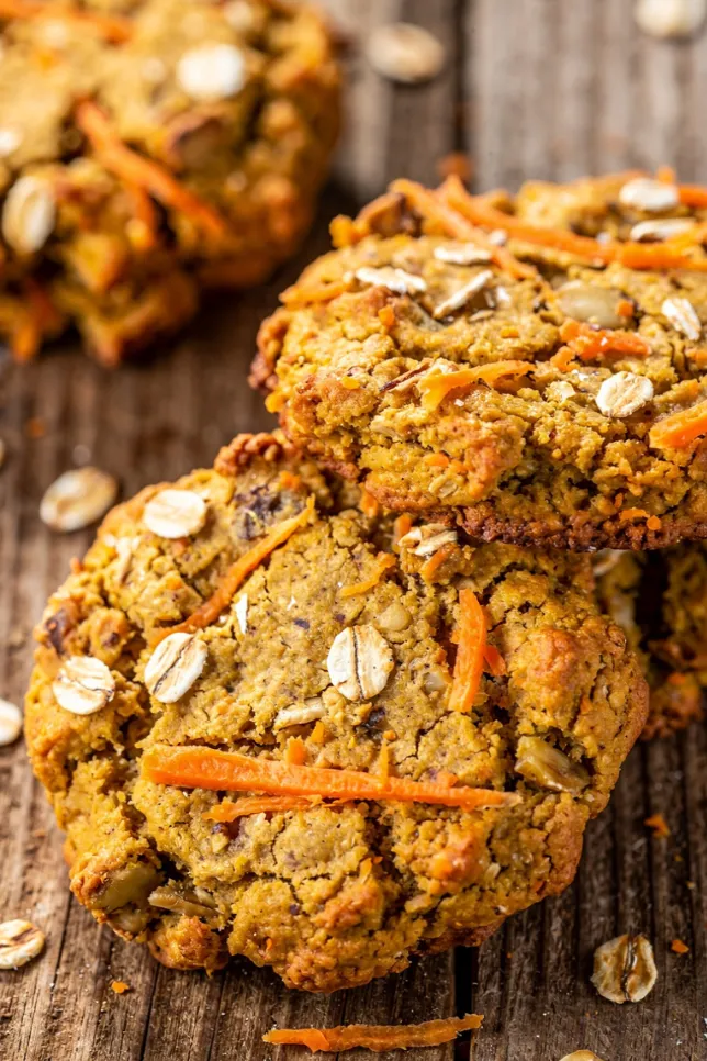 Stack of baked carrot, oat and banana cookies with one cookie broken in half showing the soft interior