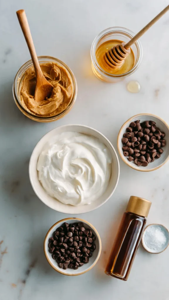 Ingredients for frozen Greek yogurt peanut butter bites including natural peanut butter, Greek yogurt, honey, and chocolate chips