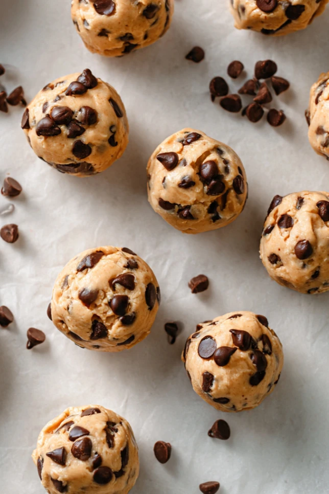 Healthy frozen Greek yogurt peanut butter bites with chocolate chips in a white bowl, some broken in half to show creamy interior