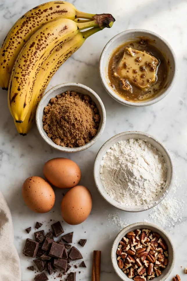 Flatlay of ripe bananas, browned butter, pecans, and chocolate chunks for banana bread